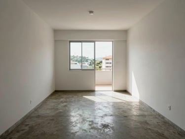 Interior living room of a compact apartment in Itajaí, natural mid-morning window light, concrete flooring, white walls, open layout without furniture staging