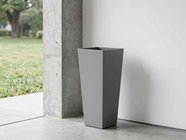 A tall matte-grey rectangular fibre planter standing next to a raw concrete column in a minimalist gallery, soft natural light, sharp focus
