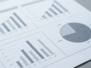 Macro detail shot of a printed statistical report with clear data charts, clean workspace, cool diffused daylight, desaturated slate tones.