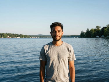 Candid portrait of a man standing near the blue waters of Lake Placid, warm natural light, 35mm.