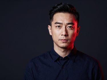 High-contrast editorial portrait of a male creative director in a dark navy studio setting, sharp details, 35mm lens