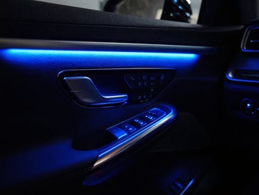 Close-up of installed neon blue LED ambient lighting glowing in a dark luxury car cabin, deep shadows, sharp details, 35mm lens