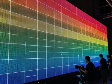 Close-up of a massive LED wall during color-calibration, sharp technical grid lines visible on screen, technical crew silhouetted in low-key lighting.