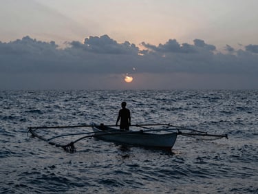 Pescador local en una panga con redes de pesca al amanecer en San Quintín, silueta dramática contra el sol naciente sobre el mar agitado.