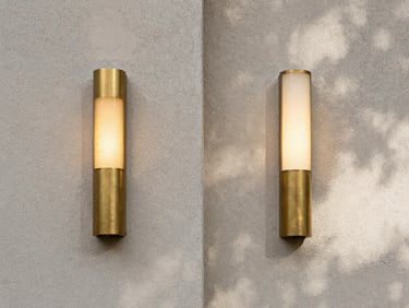 Symmetrical architectural composition, diffused natural daylight casting soft shadows on a textured plaster wall, matte brass fixture glowing softly to the left.
