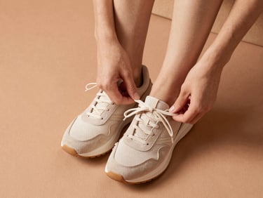 Overhead shot of a person tying comfortable sneakers, soft natural lighting, warm terracotta tones