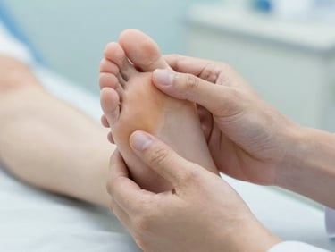 Close-up of clean hands gently examining a patient's foot under soft clinical light, shallow depth of field.