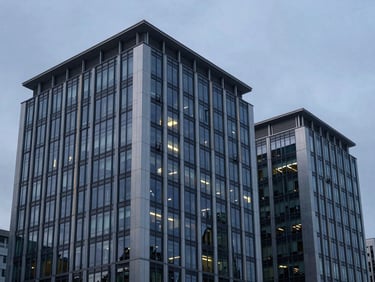 Modern corporate headquarters with a high-contrast glass facade and structural steel elements, sharp overcast daylight