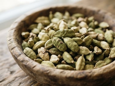 Close-up macro shot of raw green cardamom pods in a wooden bowl, bright natural daylight, shallow depth of field, 35mm