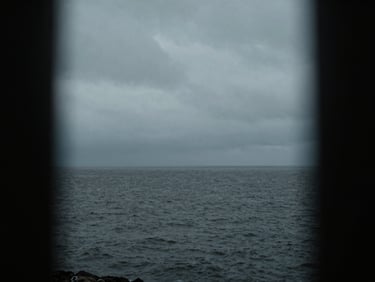 Moody cinematic shot of Dublin bay under an overcast sky, low-key dramatic lighting, desaturated cool tones, anamorphic lens framing, high contrast, 35mm grain
