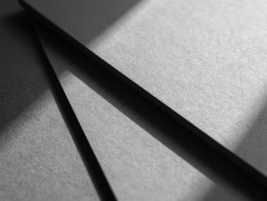 Extreme close-up of premium textured matte paper layers casting sharp architectural shadows, high-contrast grayscale studio lighting