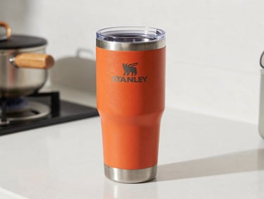 Portable Stanley-style insulated tumbler cup on a kitchen counter, bright natural light, vivid color on a clean white background
