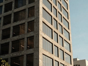 Architectural detail of a modern concrete and glass office building in São Paulo, soft shadows, clear blue sky, professional editorial style