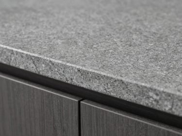 Close-up detail of a polished grey stone worktop edge with waterfall finish, studio-quality even lighting revealing grain and texture, no people, minimal background, tight macro framing