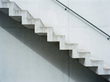 Minimalist architectural detail of concrete stairs and sharp shadows, soft overcast daylight, cool desaturated tones, 35mm