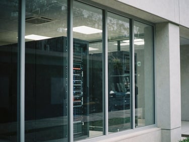 A modern server room seen through a glass partition in an academic building, sharp architectural lines, cool daylight