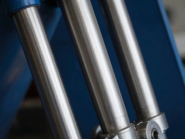 Close-up of a heavy machinery hydraulic piston, sharp technical photography, high-contrast industrial lighting, desaturated steel and deep blue tones, macro lens detail, 35mm