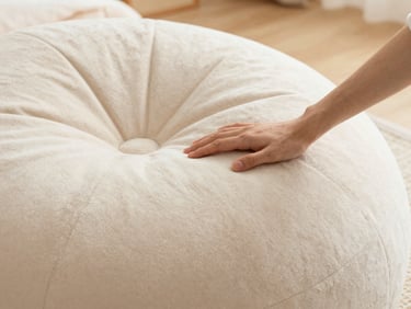 Close-up of a hand gently touching soft, patterned faux fur texture on a bean lounger, warm ambient light.