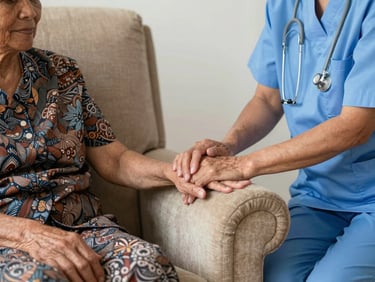 Warm editorial photography of a professional caregiver gently holding the hand of an elderly Indonesian woman sitting in a comfortable armchair, bright natural light, 35mm lens.
