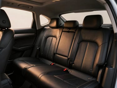 Interior cabin of an executive sedan, pristine black leather seating, warm amber ambient lighting glowing softly.