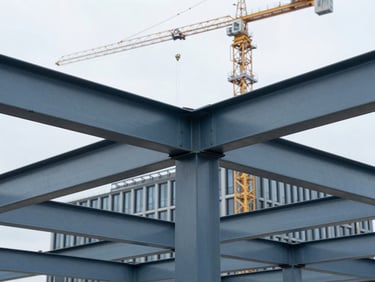Close-up of structural steel beams being erected for a commercial office building in an urban Dutch setting, natural overcast daylight, cool blue and slate tones, sharp focus, 35mm, with a crane in the background