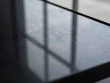 Extreme close-up of a dark glass surface reflecting a faint architectural grid, cool silver tones, depth through reflection, minimal, no text