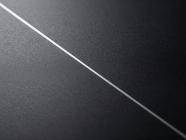 Close overhead study of a matte black surface with a single thin silver geometric line etched into it, extreme contrast, no text, architectural abstraction