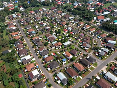 Wide daylight overhead site plan view of a residential subdivision in Tangerang Selatan, paved internal roads visible, plotted land parcels clearly delineated, surrounding greenery at edges