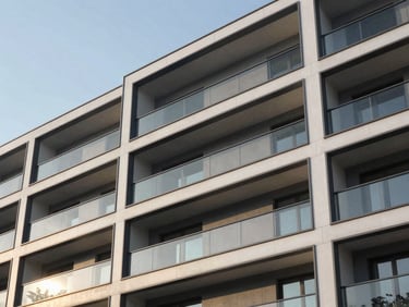 Architectural close-up of a modern residential building facade with anthracite gray panels and large glass balconies under clear daylight.