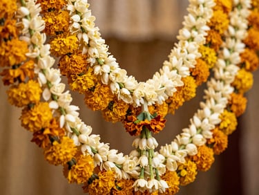 Macro shot of dense fresh-cut jasmine and marigold garlands hanging in layers, soft focus background of a festive wedding hall, warm editorial lighting.