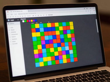Screenshot of a JavaScript browser game — a grid-based puzzle with bright colored blocks, score counter visible at the top, running in a browser tab on a laptop screen