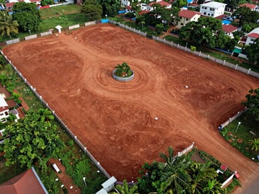 Aerial drone shot of open residential plots in a gated community layout near Vizianagaram, boundary markers visible, red laterite soil, surrounding greenery