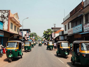 Environmental shot of a main commercial road in Vizianagaram town, two-storey market buildings lining the street, midday natural light, auto-rickshaws and pedestrians creating local activity, framed wide from the centre of the road