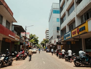 Street-level shot of a commercial corridor in Visakhapatnam, shop frontages and office building facades, midday daylight, urban activity visible