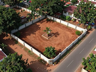 Aerial shot of a 200-square-yard residential plot in a gated layout near Vizianagaram, corner plot with two-road access, red soil, boundary wall visible, daytime natural light