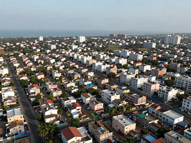 Wide aerial view of a Visakhapatnam residential neighborhood, apartment blocks and gated plot clusters visible from above, natural daylight, coastal haze on the horizon