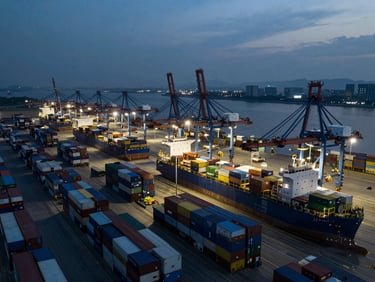 Aerial view of a massive commercial shipping hub at dusk, high-contrast cool-toned industrial lighting