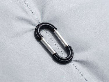 Close-up of technical waterproof fabric stitching and heavy-duty carabiner, bright daylight, sharp details.