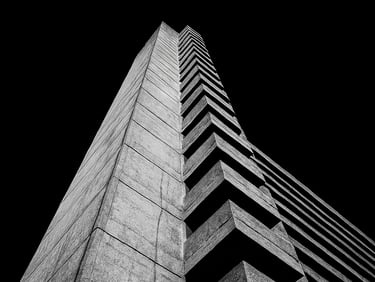 Extreme low-angle shot of a brutalist concrete tower in London, harsh direct flash, deep black sky, high contrast, black and white