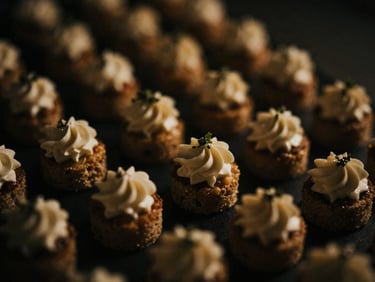 Close-up artistic shot of a small, elegantly plated appetizer, shallow depth of field, moody low-key side lighting, deep shadows, warm gold and charcoal tones