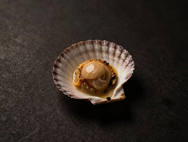 Overhead minimalist composition of a single scallop dish, artfully arranged, moody low-key side lighting, deep shadows, warm gold and charcoal tones
