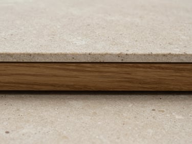 Extreme close-up of a raw travertine floor slab meeting a wire-brushed oak threshold, straight-on elevation, soft natural daylight.
