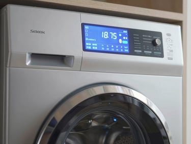 Sleek close-up of a modern digital touch interface on a high-end front-load washer-dryer, soft blue LED lights reflecting on brushed metallic steel, clean and sophisticated composition.