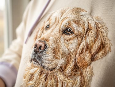 Extreme close-up of machine embroidery on a hoodie, showing dense stitches of a pet portrait, soft morning window light, shallow depth of field, cozy cream and lavender tones