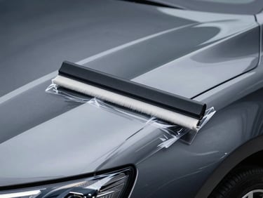 Extreme close-up macro shot of a clear protective film being squeegeed onto a flawless dark metallic car hood, dramatic linear rim lighting, 85mm
