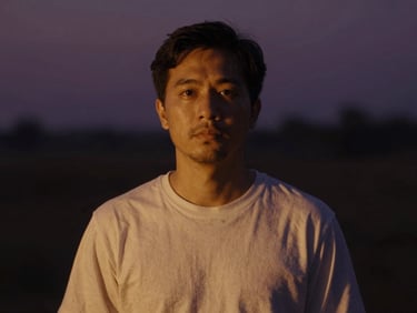 Cinematic portrait of a male sound therapist, warm amber lighting, soft focus, 35mm lens, atmospheric dark background