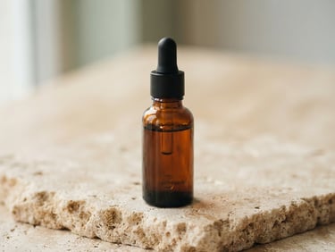 Macro close-up of a minimalist amber glass dropper bottle on a raw stone surface, soft morning light casting gentle shadows, warm alabaster background, shallow depth of field, 35mm photography