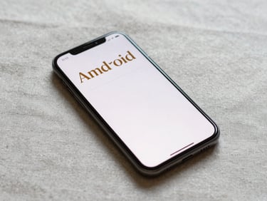 Overhead shot of an Android phone on a pale linen surface, screen showing a simple reading-progress tracker with warm amber typography, no hands, diffused daylight from above