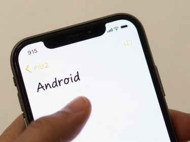 Close-up of Android phone screen displaying a minimal note list with two lines of handwritten-style text visible, thumb hovering over the screen, soft diffused studio light, warm off-white background