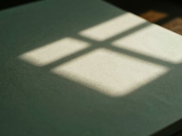 Subdued editorial photograph, soft natural window light casting architectural shadows on a heavy paper document, deep forest green tones, macro close-up, 35mm